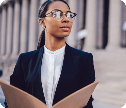 A woman in glasses and a suit holding papers.