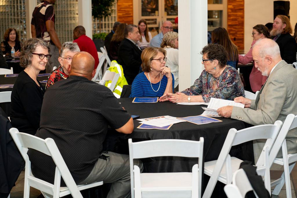 A group of people sitting at tables with papers.